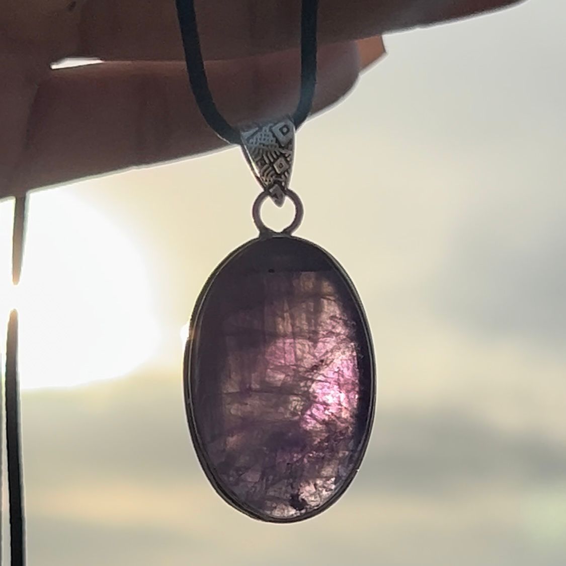 Necklace with an oval pendant against a blurred natural background