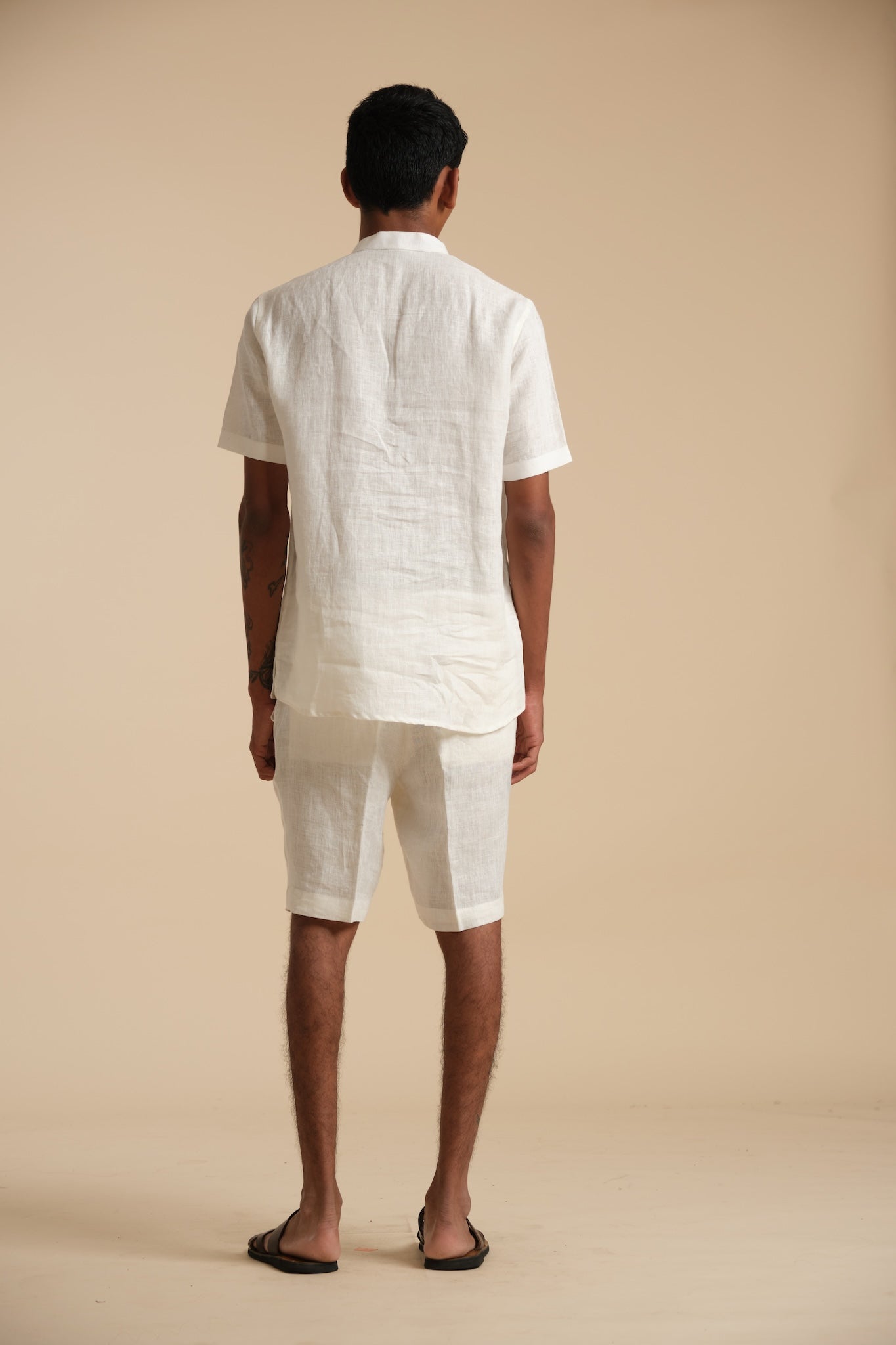 Man wearing a white linen outfit on a beige background