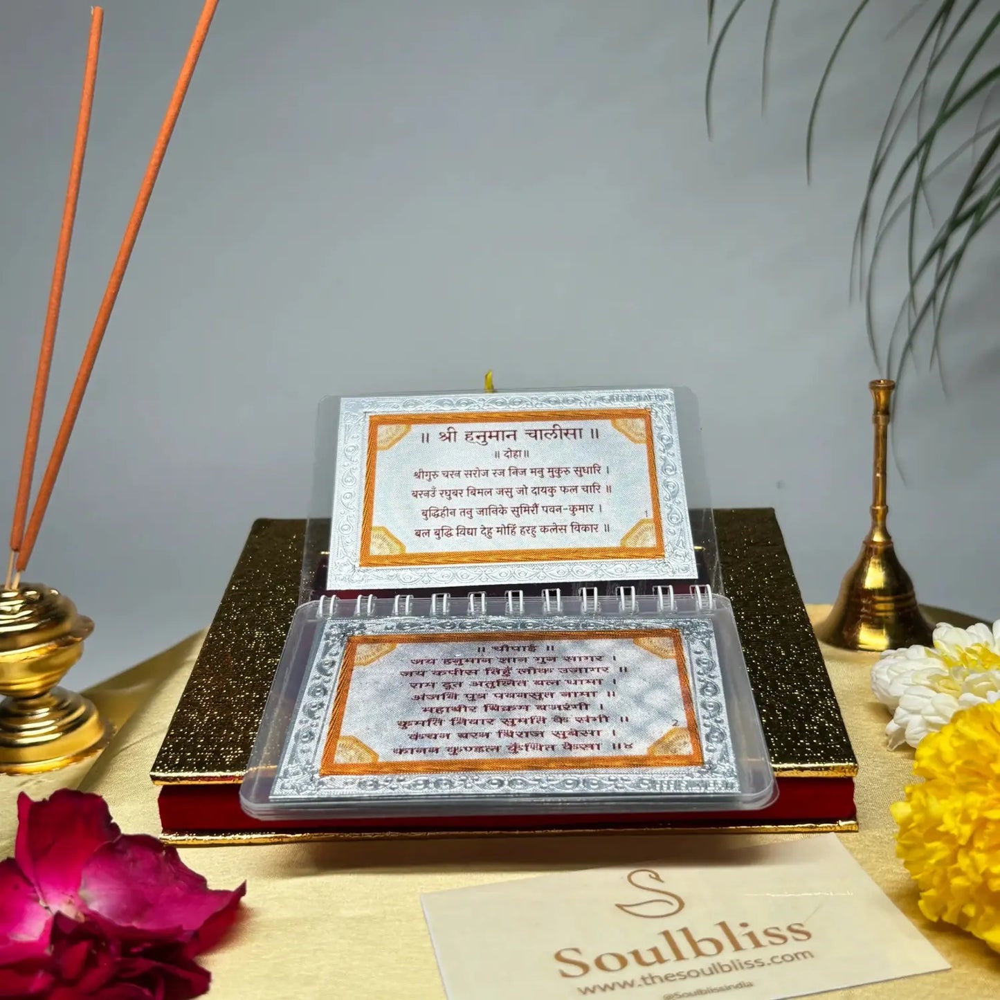 Decorative set with incense sticks, flowers, and a book titled 'Soulbliss' on a gray background.