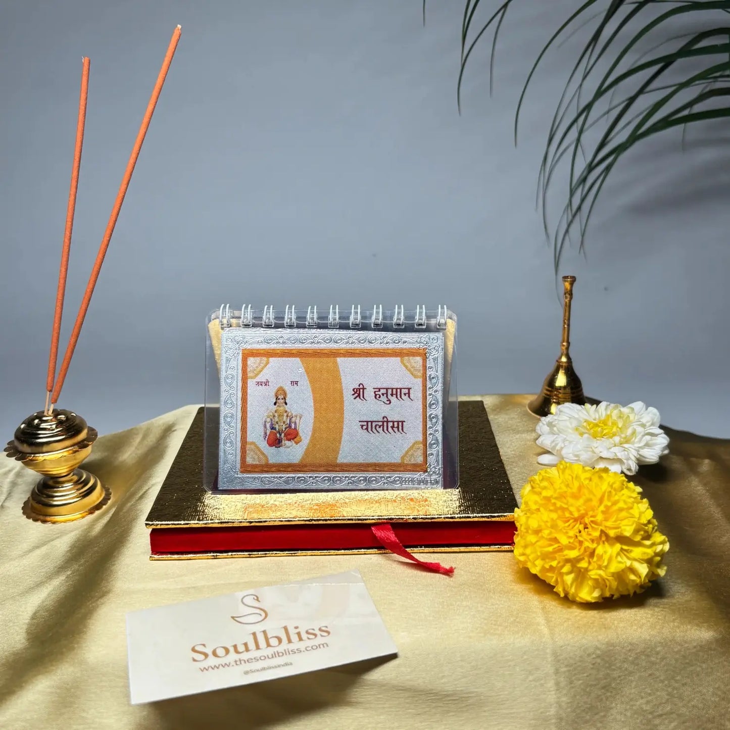Decorative setup with a book, incense sticks, and flowers on a table.