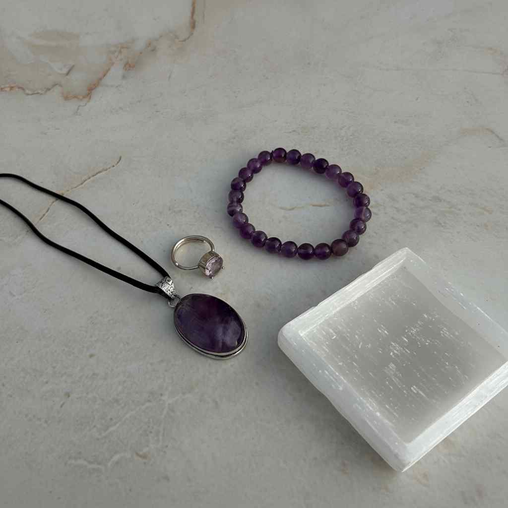 Amethyst jewelry set with necklace, bracelet, and ring on a marble surface