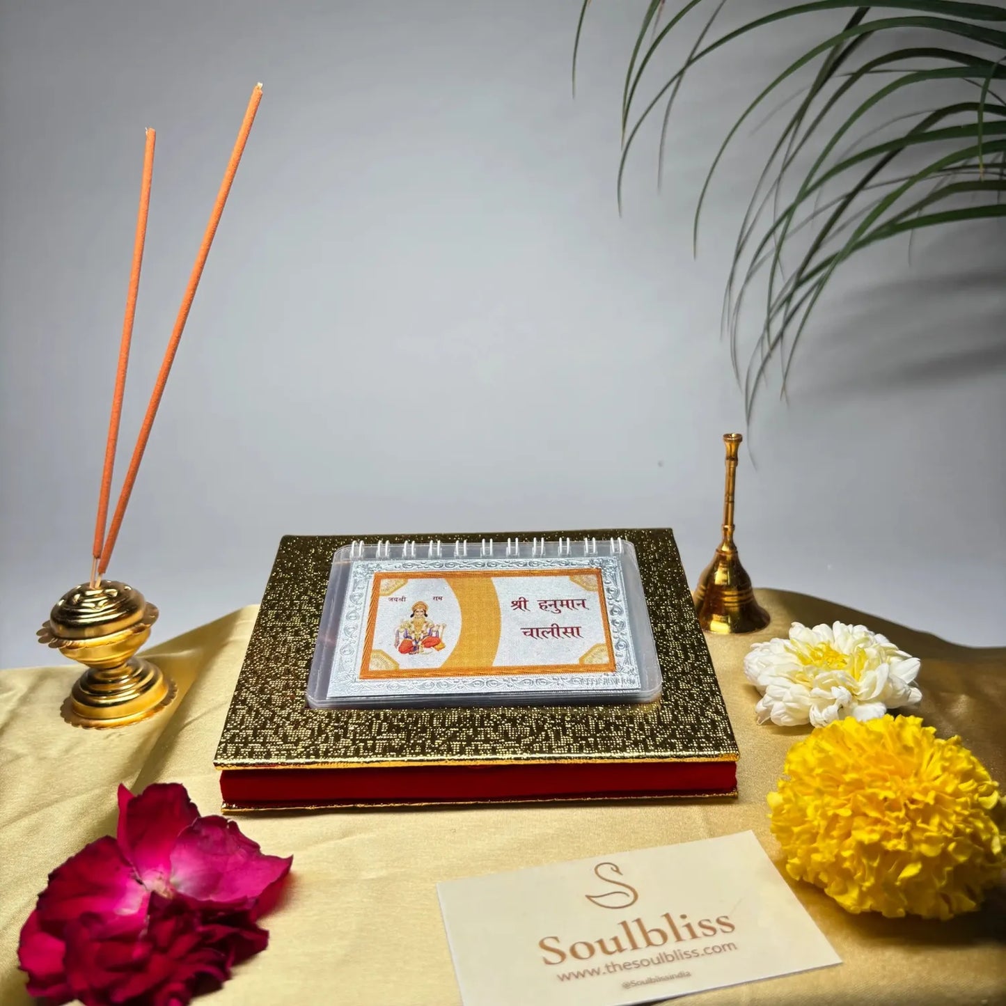 Decorative setup with incense sticks, flowers, and a card on a table with a gray background.