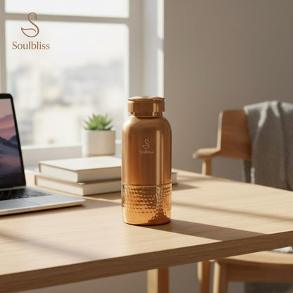 Gold water bottle on a desk with a laptop and books, featuring the 'Soulbliss' brand.
