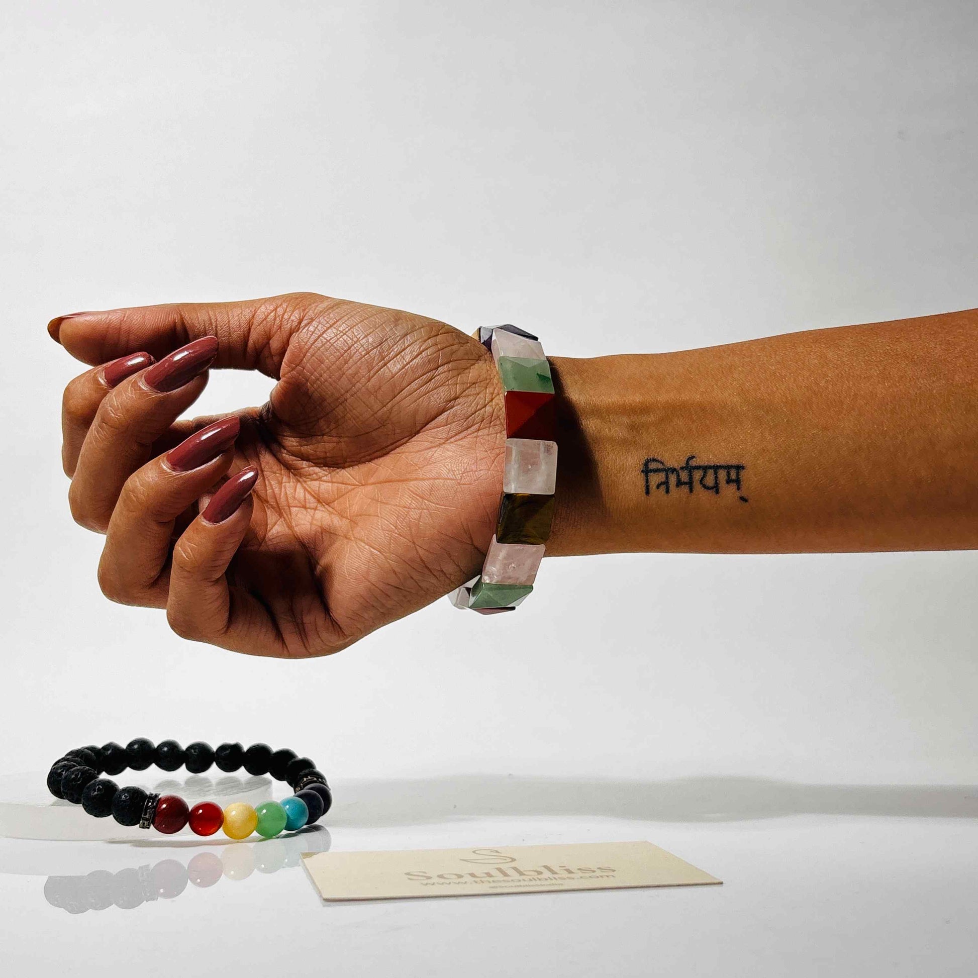 Hand wearing a colorful bracelet with a plain background