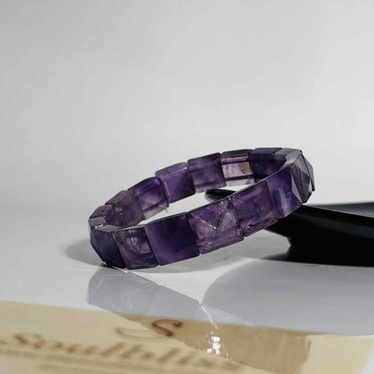 Purple beaded bracelet on a white surface with a blurred background