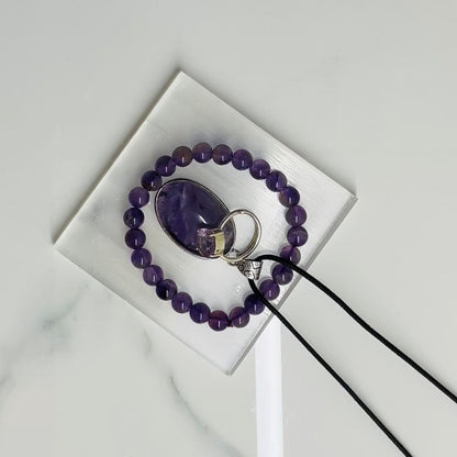 Purple beaded bracelet with a mirror and ring on a white surface