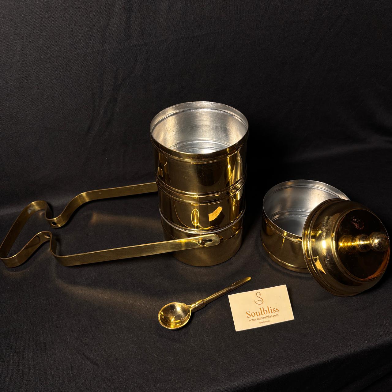 Gold and  brass tiffin set with a spoon on a black background