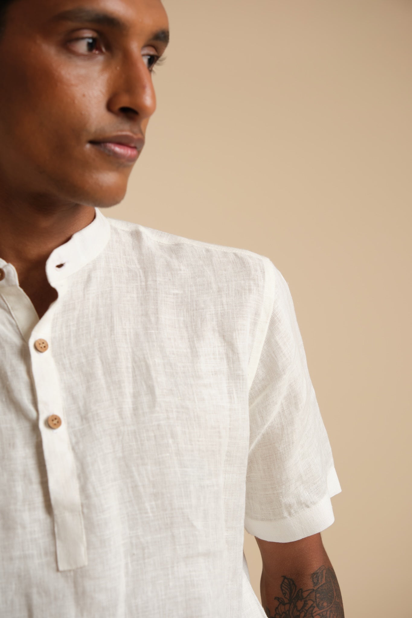 Man wearing a white shirt with a beige background