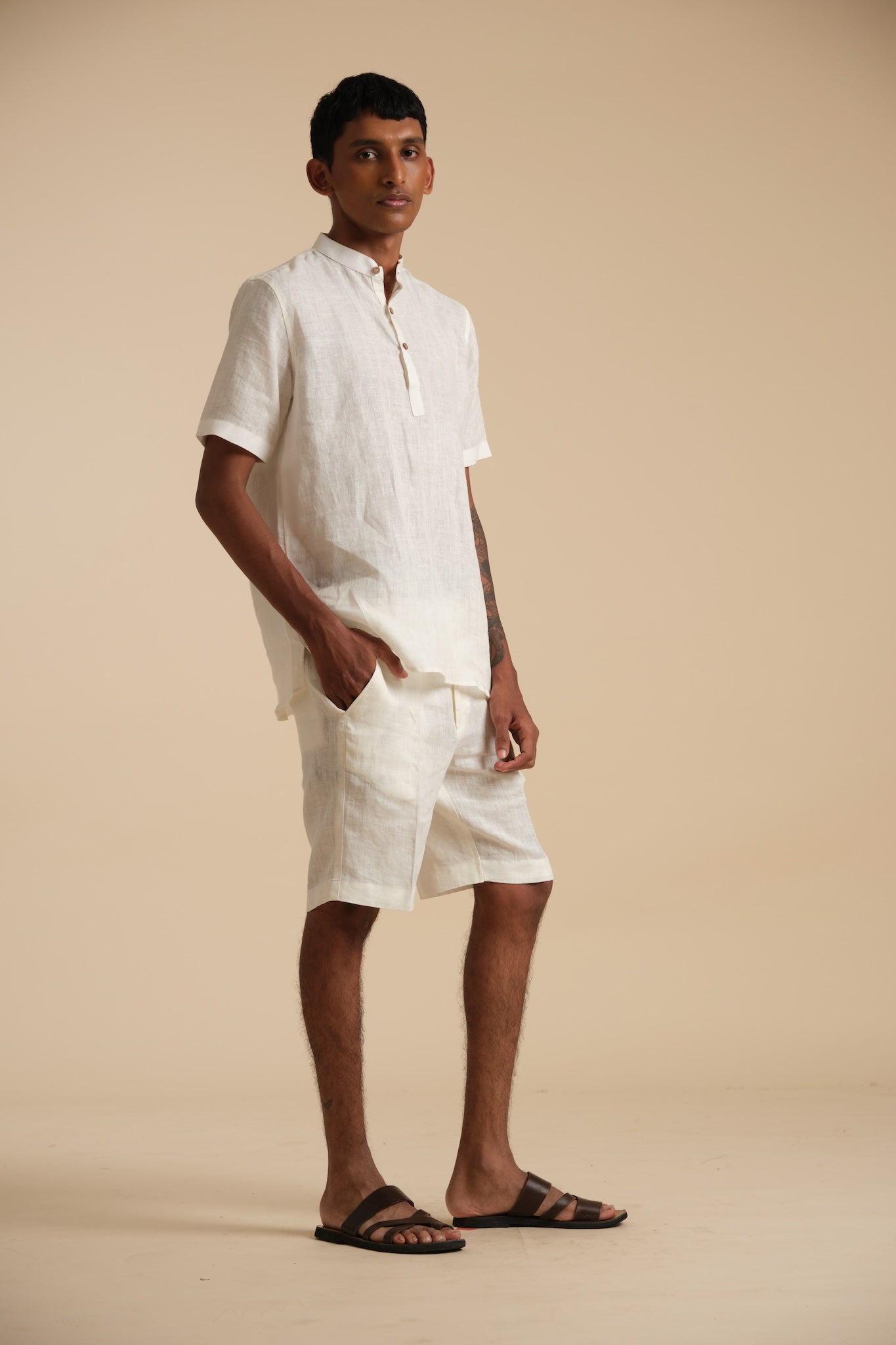 Man wearing a white linen outfit on a beige background