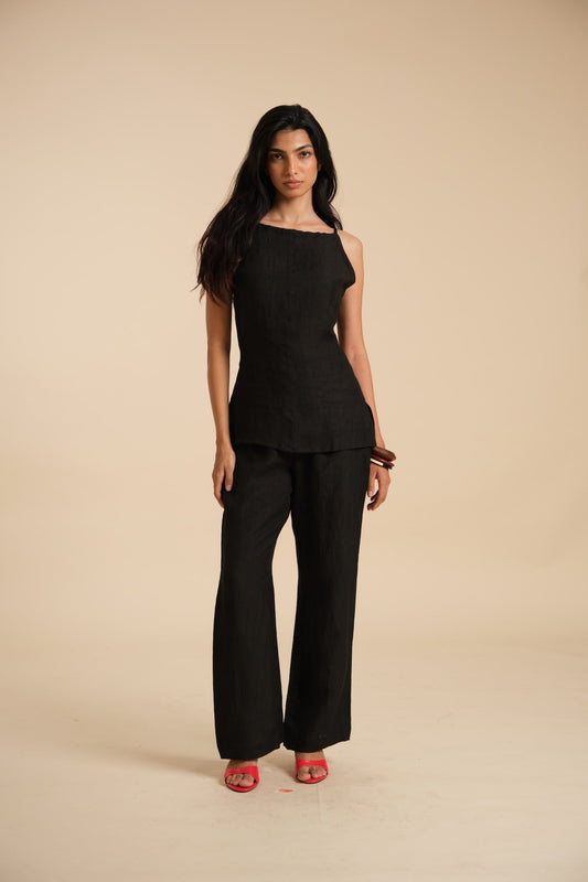 Woman wearing a black linen outfit on a beige background