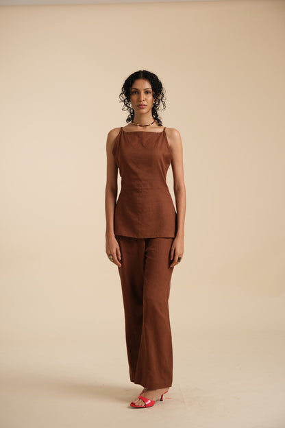 Woman wearing a brown sleeveless top and wide-leg linen pants on a beige background