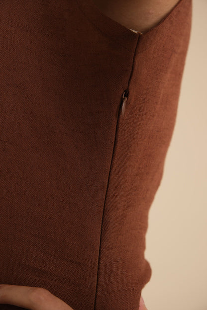 Close-up of a brown linen garment with a zipper on a beige background