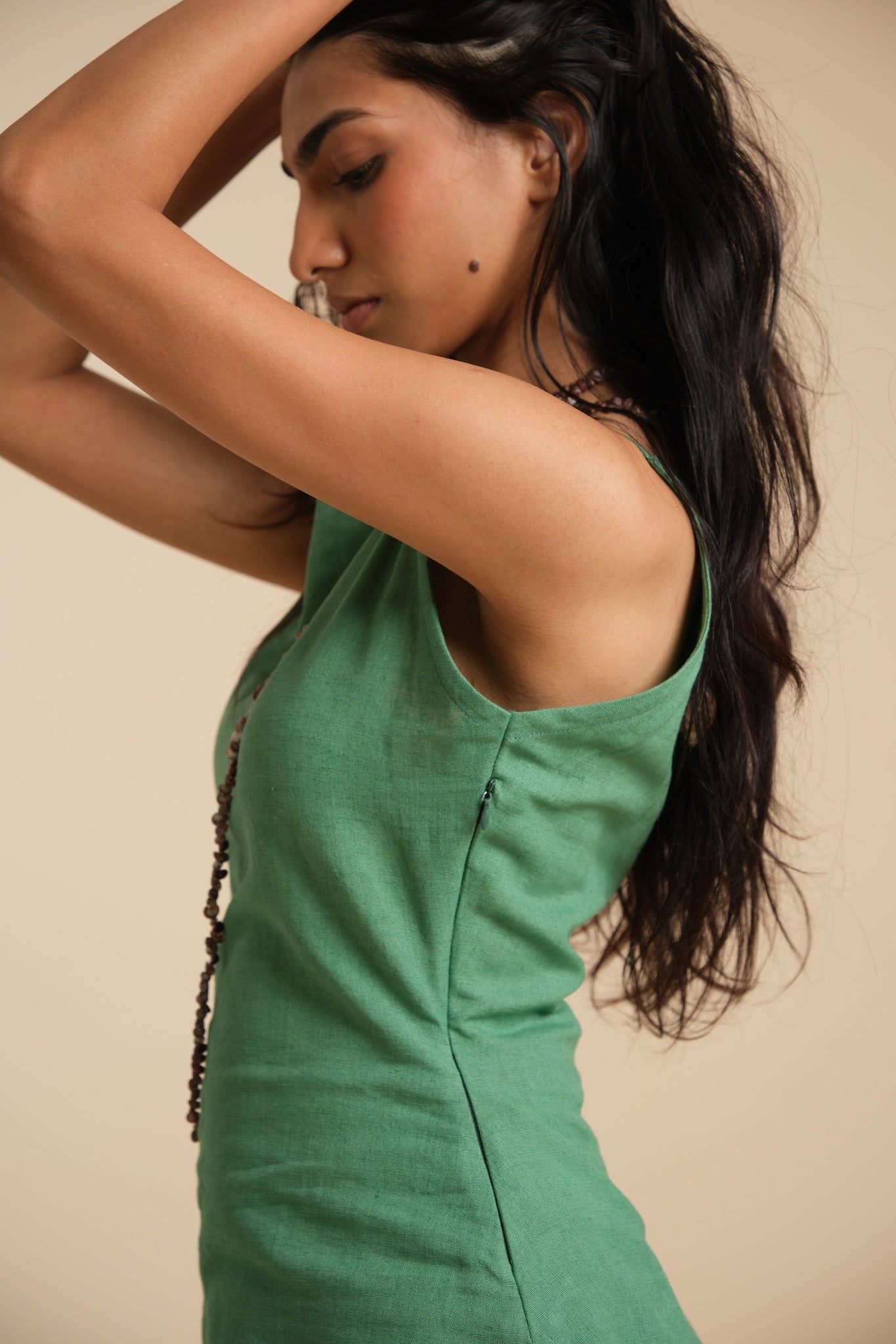 Woman wearing a green dress against a beige background