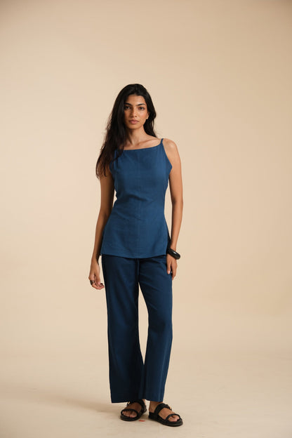 Woman wearing a blue sleeveless top and pants on a beige background