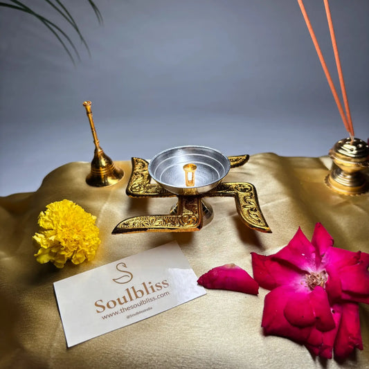 Decorative setting with gold lamp, flowers, and incense on a textured surface with 'Soulbliss' branding.