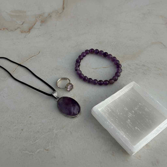 Amethyst jewelry set with necklace, bracelet, and ring on a marble surface