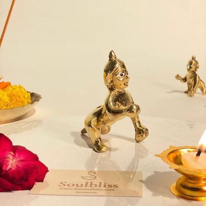 Gold figurine of a bal gopal with a 'Soulbliss' card and candles in the background.