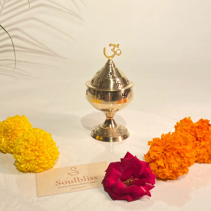 Gold incense burner with flowers on a white surface