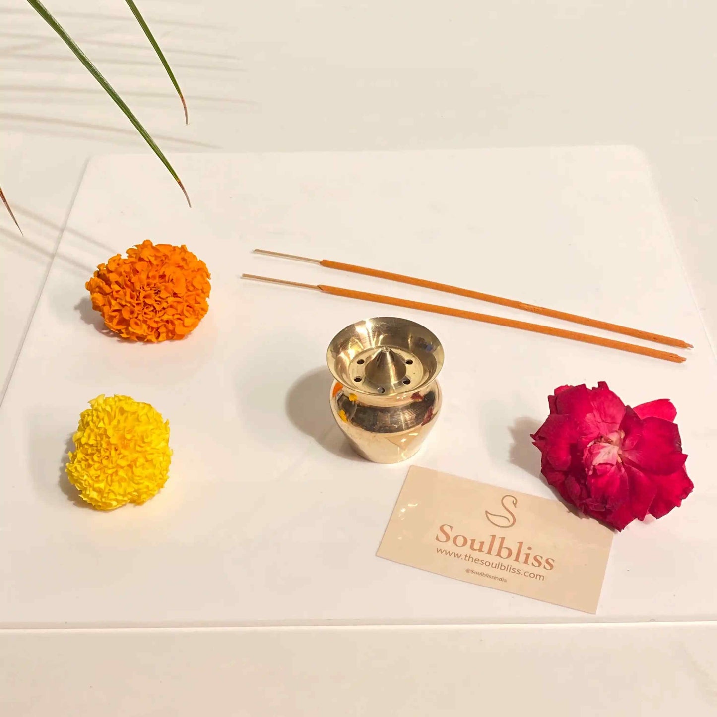 Decorative items including a gold incense burner, flowers, and incense sticks on a white surface with 'Soulbliss' branding.