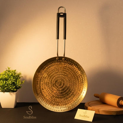 Decorative gold pan with a plant and rolling pin on a dark surface, branded 'Soulbliss'.