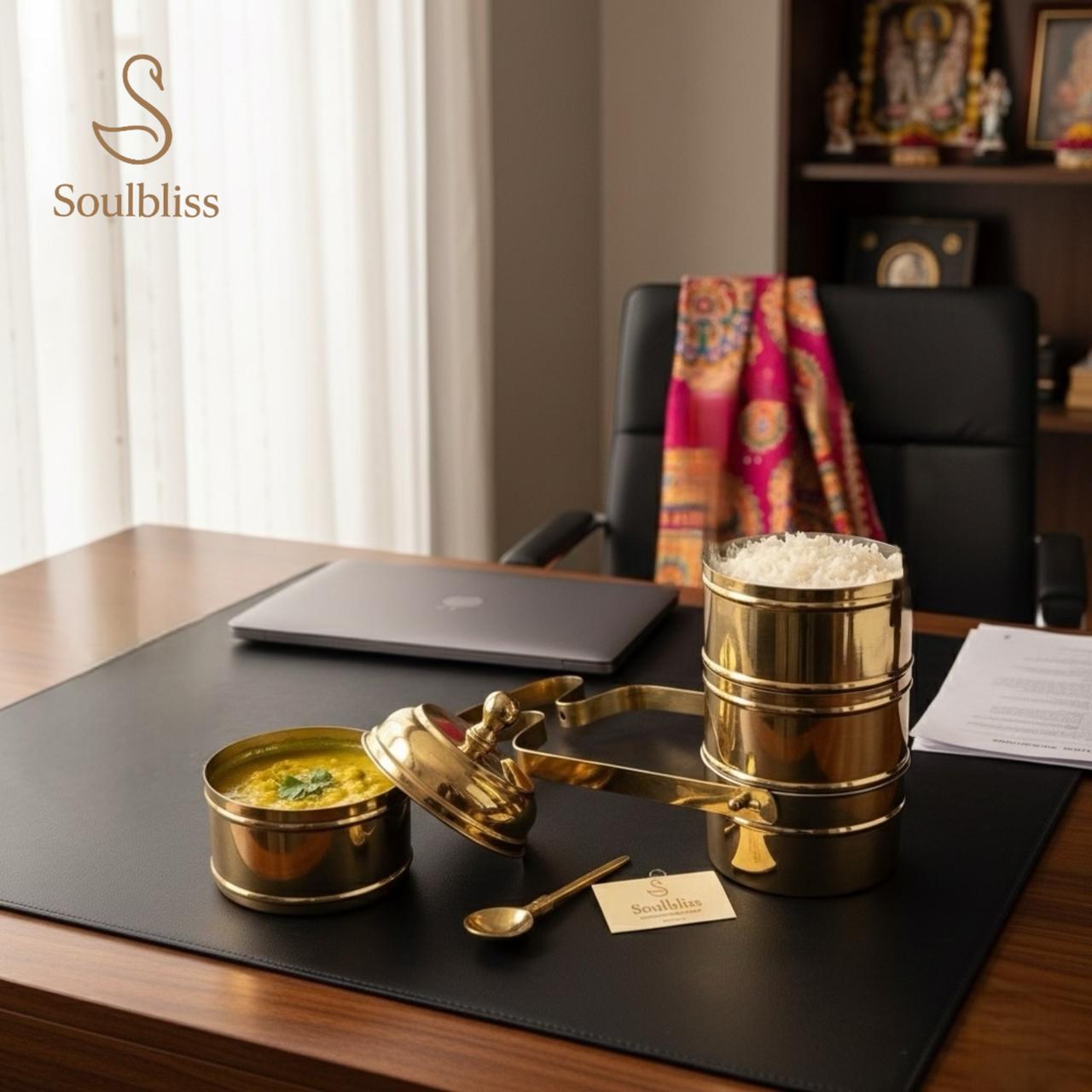 Gold temple offering tray with food in brass tiffin on a desk, featuring the 'Soulbliss' brand.