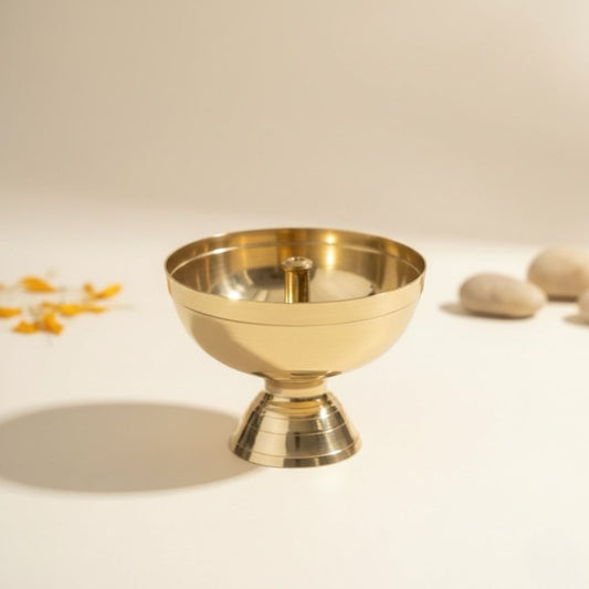 Gold decorative brass puja diya on a beige background