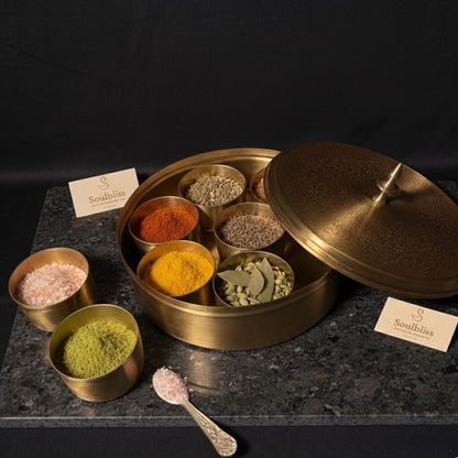 Spice set in a brass container with various spices on a dark surface, branded 'Soulbliss'.