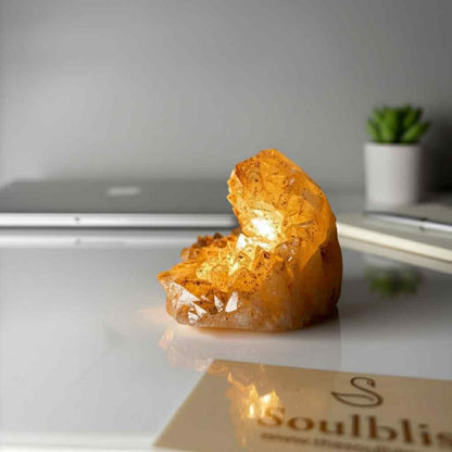 Orange crystal on a reflective surface with a blurred background