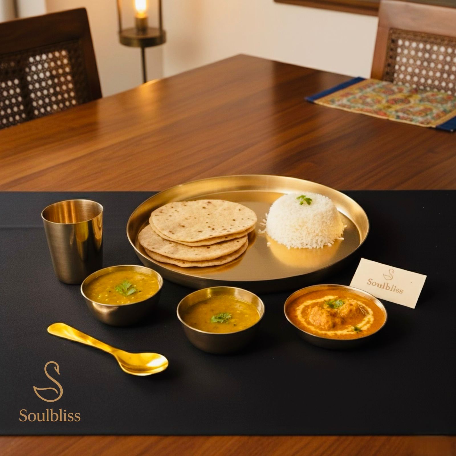Dinner setup with gold platter, bowls, and a glass on a black surface with 'Soulbliss' branding.