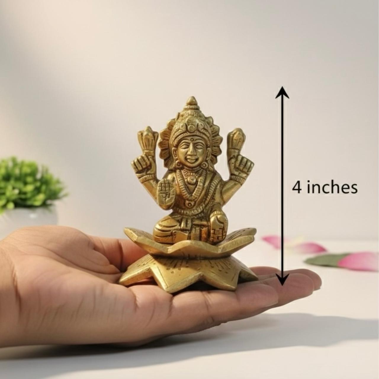 laxmi ji brass statue held in a hand with a measurement label indicating 4 inches.