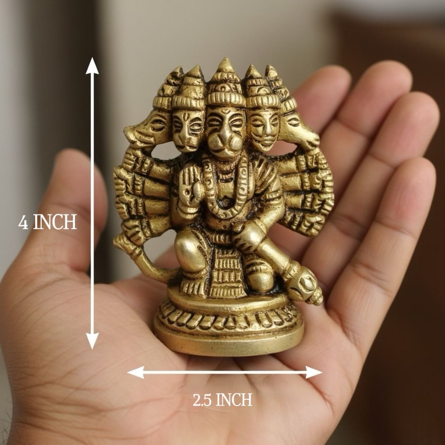 Small gold-colored statue of hanumanji held in a hand with measurements indicated