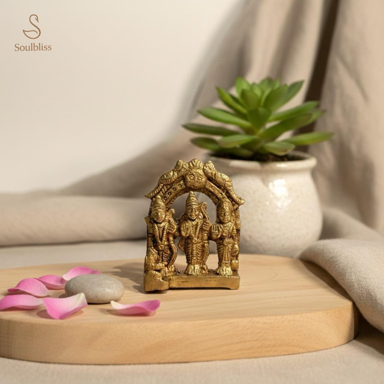 ram darbar Gold figurine on a wooden surface with pink petals and a plant in the background
