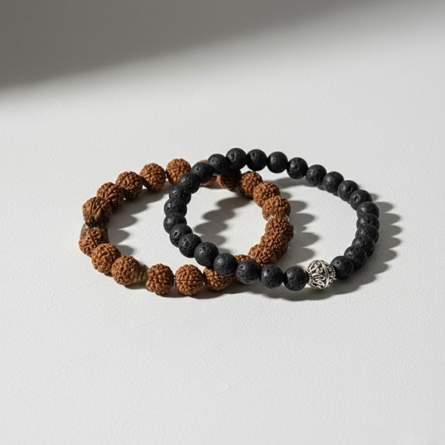 Two beaded bracelets, one with brown beads and the other with black beads, on a light surface.