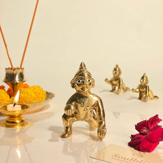 Gold figurine with incense sticks, flowers, and a card on a light background